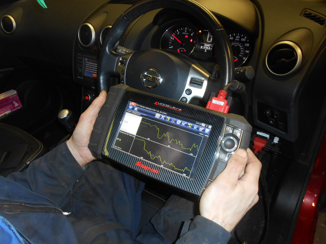 Diagnostic device in use near a Nissan dashboard
