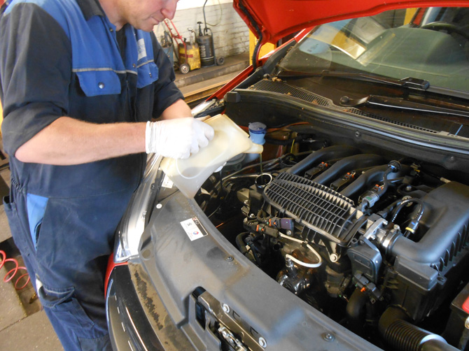 Technician working under the bonnet of a Peugeot