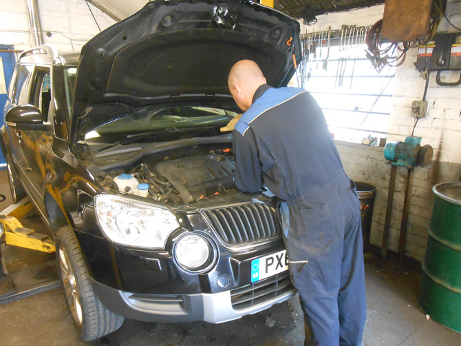 Mechanic leaning into the engine bay of a Škoda in the workshop
