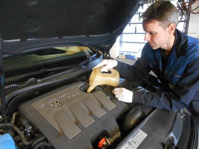 Mechanic working under the bonnet of a VW at Golden Hill Garage
